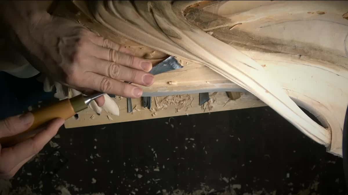 One hand presses a wide flat blade level on the edge band while the other holds its handle