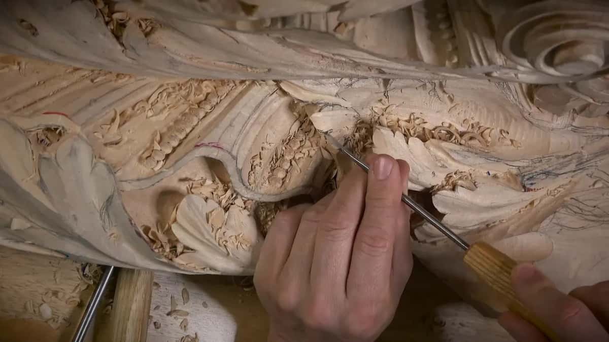 Pale handle and slim shaft angled into a hollow between lobes, shavings piled beside it