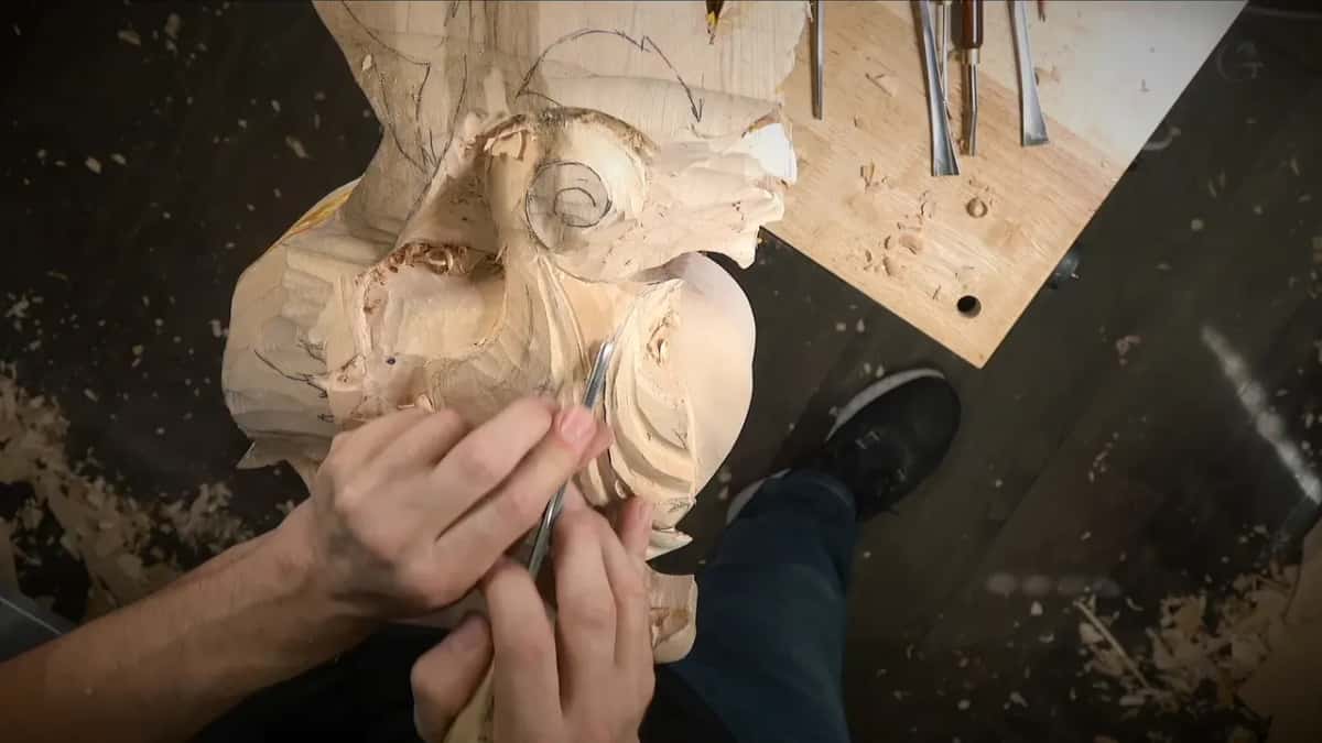 Left fingers brace a small tool while it works in close, just under the scroll
