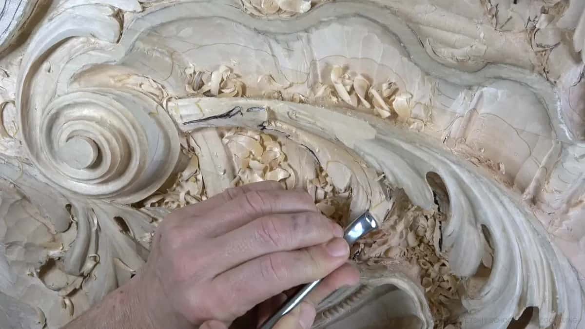 At the lower left a short steel tool reaches deep into a lobe, chips piling around it.