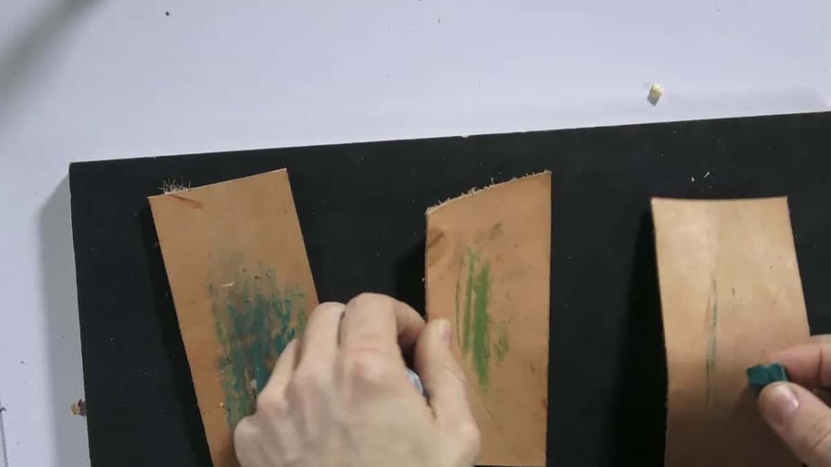 Black board holding three leather pieces, each charged a different color.