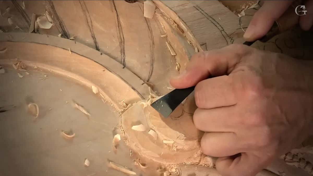 Flat chisel shaving the edge of the round head, chips lying on the ground