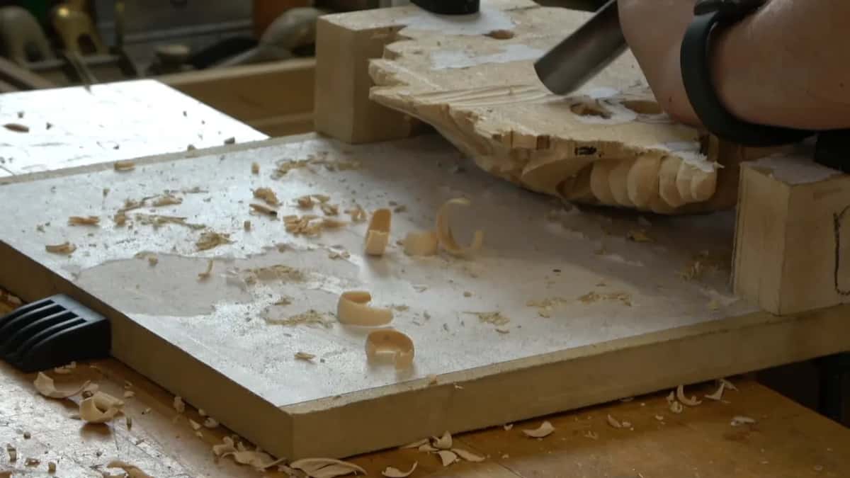 Gouge working the back, curls of wood on the white board