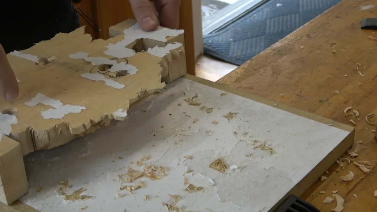 Carving face down on a paper covered board, white paper still stuck to its back