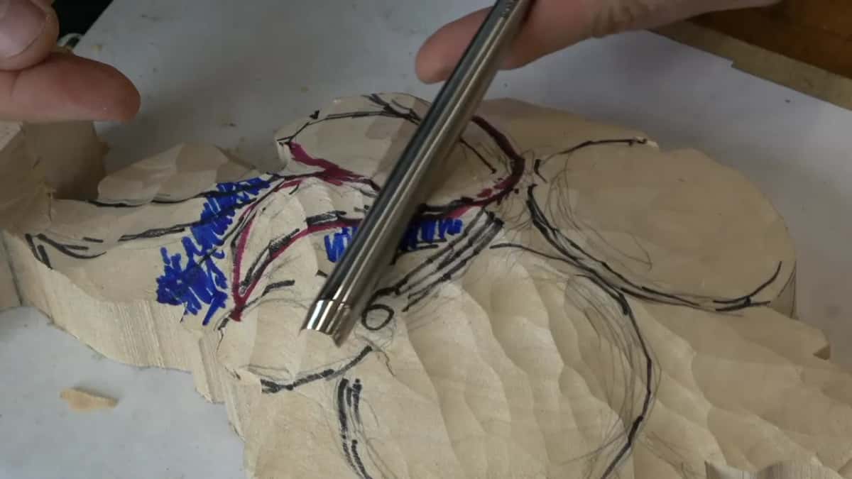 Gouge held point down on the drawn blank, its lines in black, red and blue