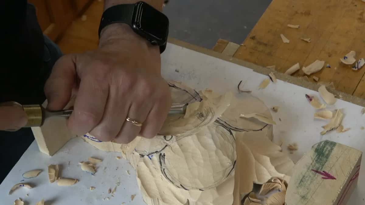 Tool with a brass ferrule held low across the faceted dome, chips spread over the white board
