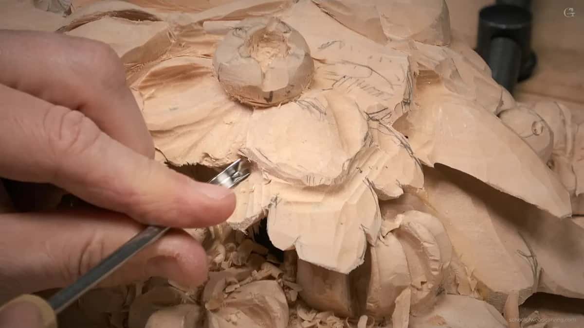 Low view, fingers holding a gouge under a petal with shavings below