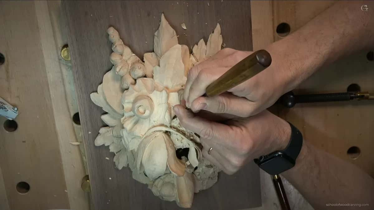 Two hands on a dark-handled tool low on the panel, a black watch on one wrist