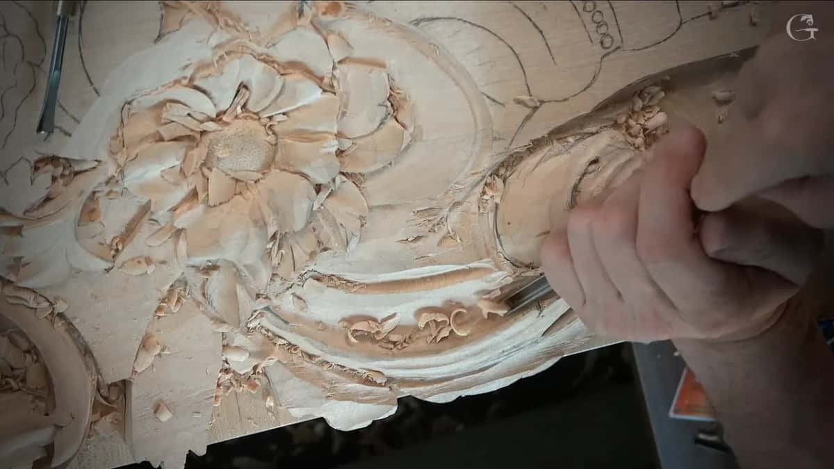 Close view, knuckles over a small tool at the rim of the scroll