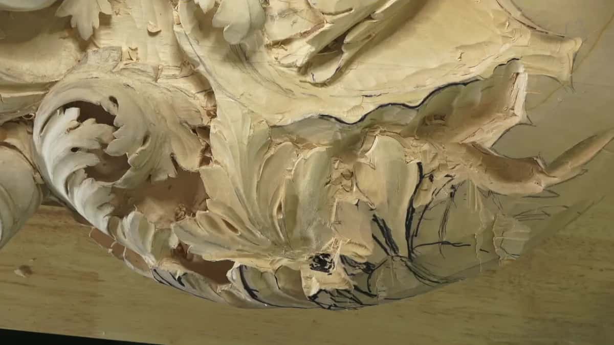 Acanthus leaves standing in high relief, pale wood, black marker lines still drawn on the part not yet carved