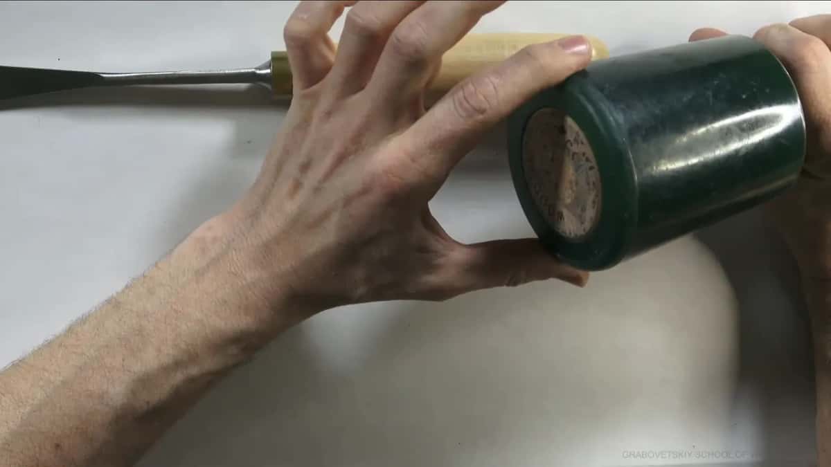 One hand on the gouge handle, the other on the mallet