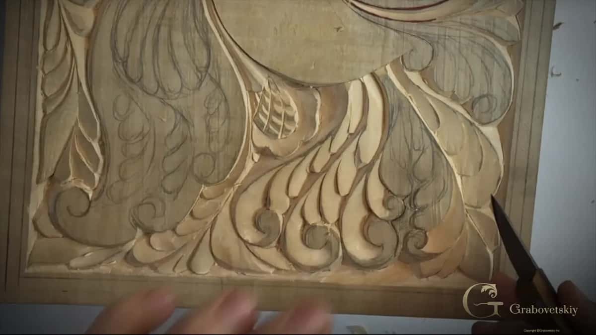Row of carved tail curls, the knife entering from the right