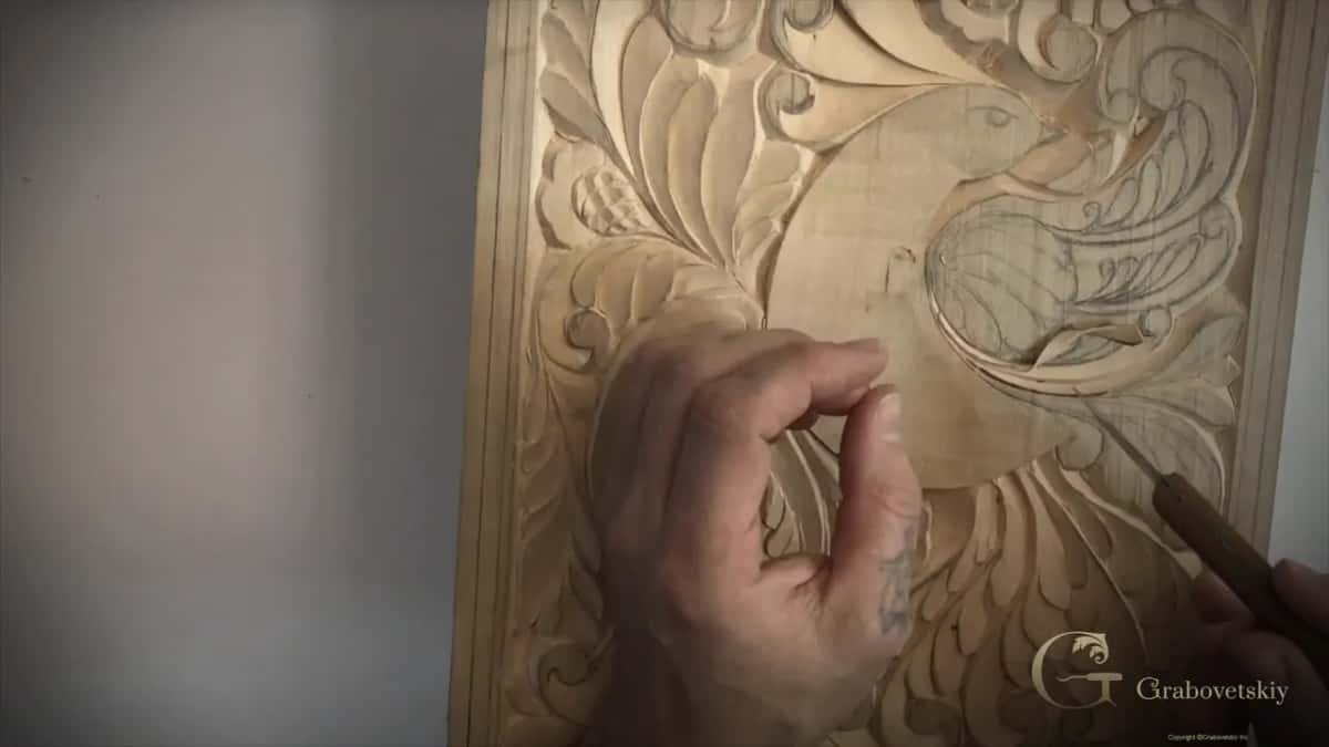 Fingers pinched together above the round body while the knife sits low at the right of the wing