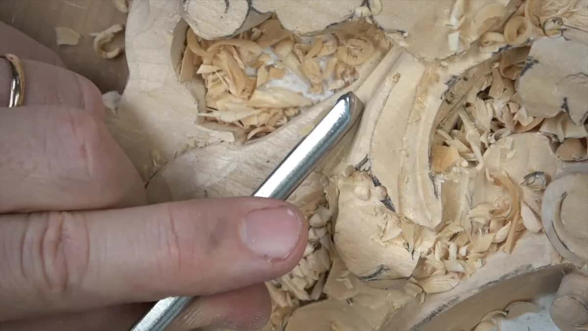 Straight gouge laid low across the leaf near a hollow, a ring on one finger