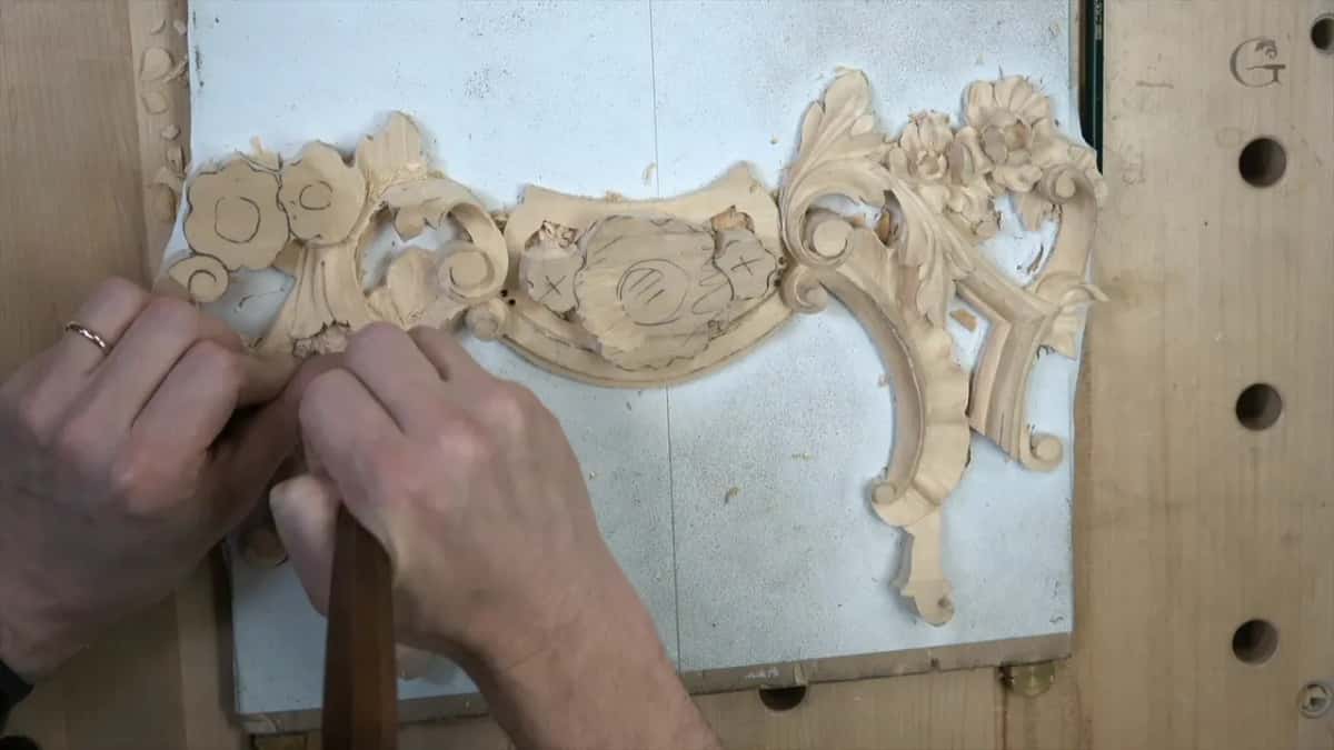 Both hands steady a brown-handled tool at the left end of the panel