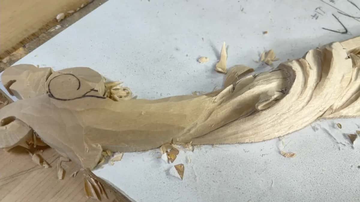 The leaf seen at an angle, its raised pipes running toward the scroll, chips on the white paper