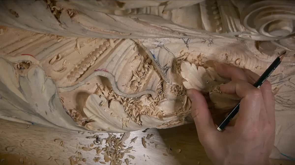 Pencil over the frieze Hand with a pencil over the carved frieze, a row of beads and a spiral above it