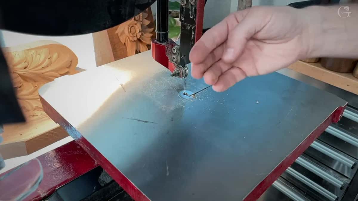 A finger points beside a hair thin blade standing in the sawdust