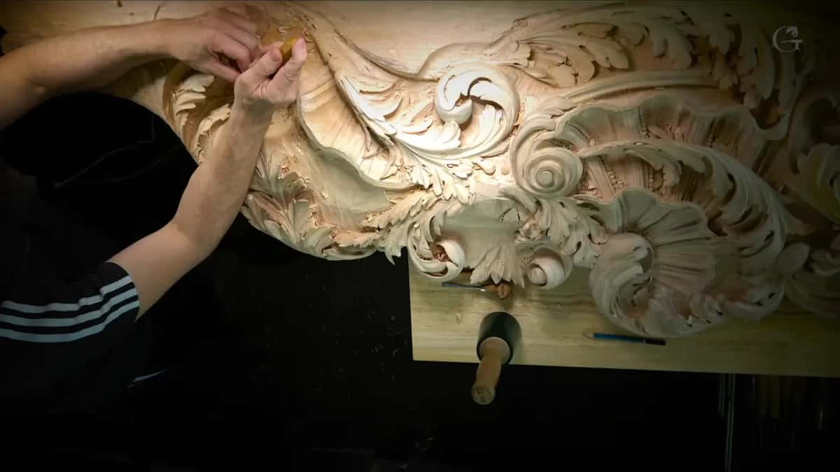 Arms laid along the top of a big carved panel