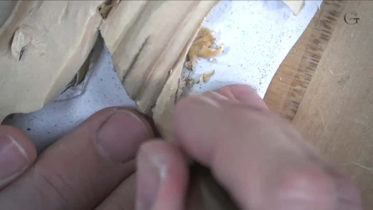 Fingertips pinch a tiny blade at the molding corner