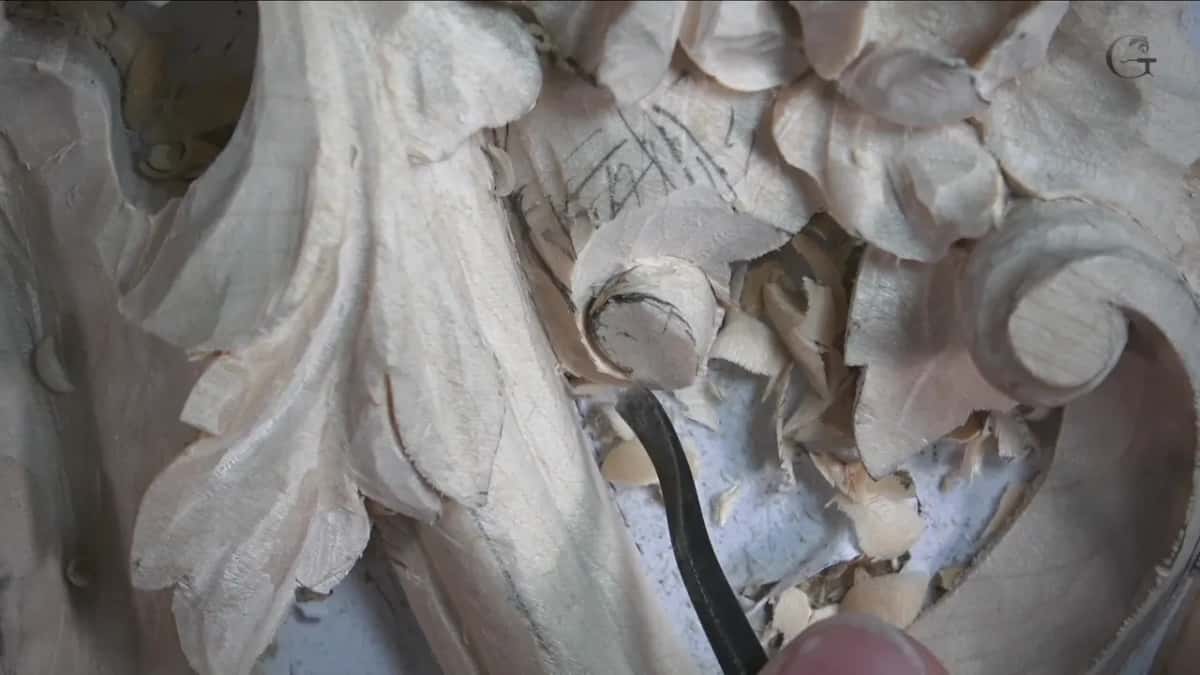 Bent black spoon tool digging beside a round stub, shavings piled up around it