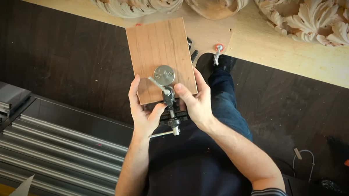 A wood block held in both hands, a round metal plate fixed to its back