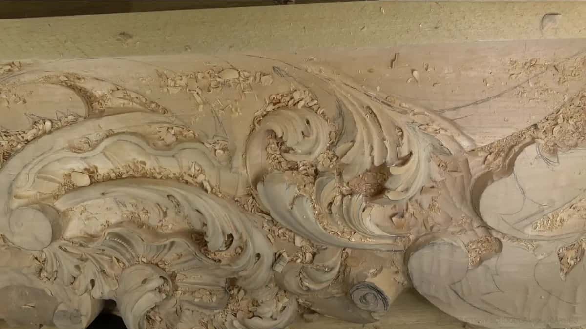 A long carving of acanthus scrolls under a layer of chips