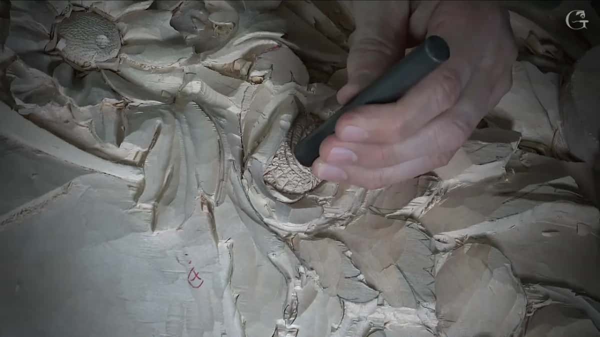 A dark punch sits in the center of a carved flower, its texture already spread through the middle.