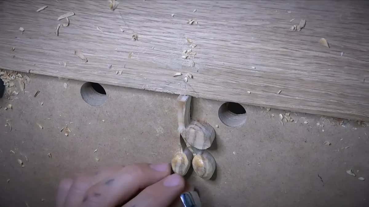 Three small olives on one stem rest against an oak board's edge.