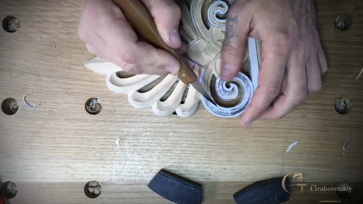 Thumb and fingers guide a knife along the outside line of the spiral