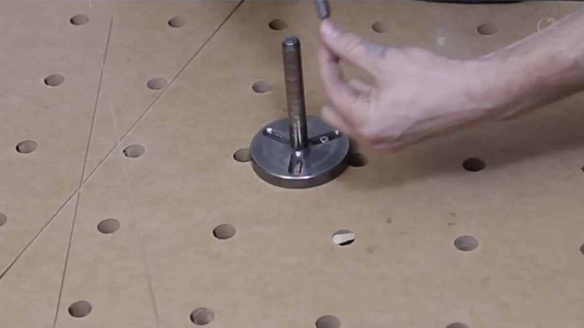 Steel post on a round base, screwed to a board full of holes