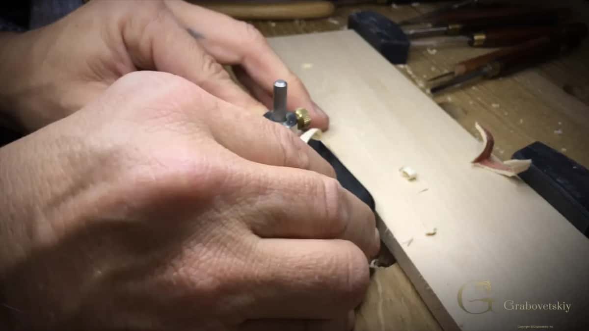 Both hands steer the plane, which rides on the spare strip, curls of shavings around.