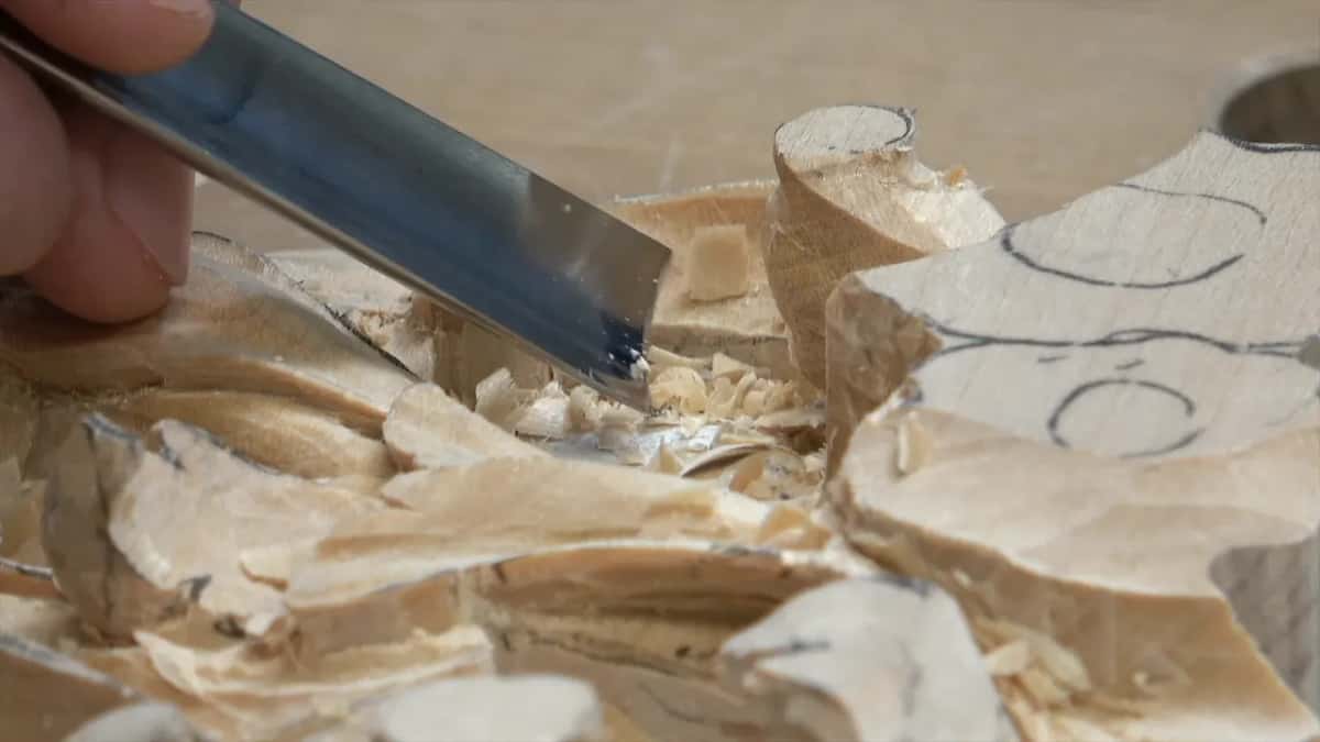 Broad blade biting beside a rounded scroll, chips piled all around it
