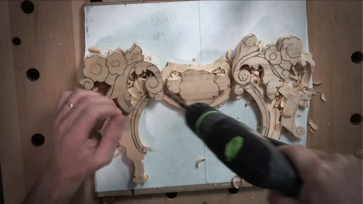Drill bit going in beside the scroll on the left, chips scattered over the white board