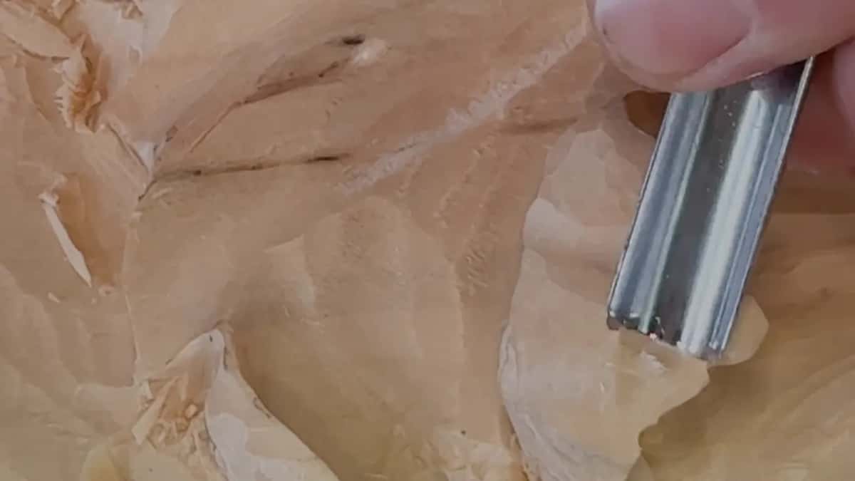 Shallow gouge resting on a smooth lobe while chips sit in the hollow beside it