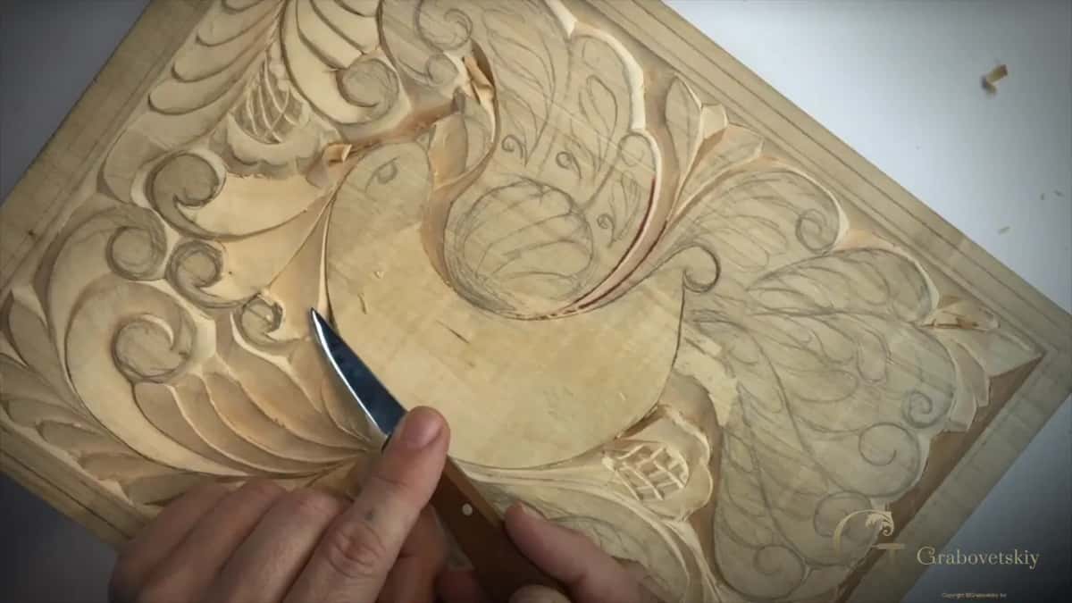 Knife resting on a long curl beside the bird, with the whole tail feathered out below it