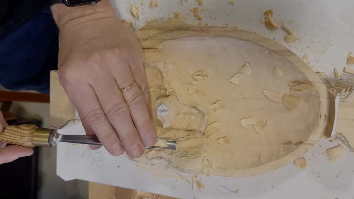 One hand pushes a gouge into the leaf while the other steadies it, top view