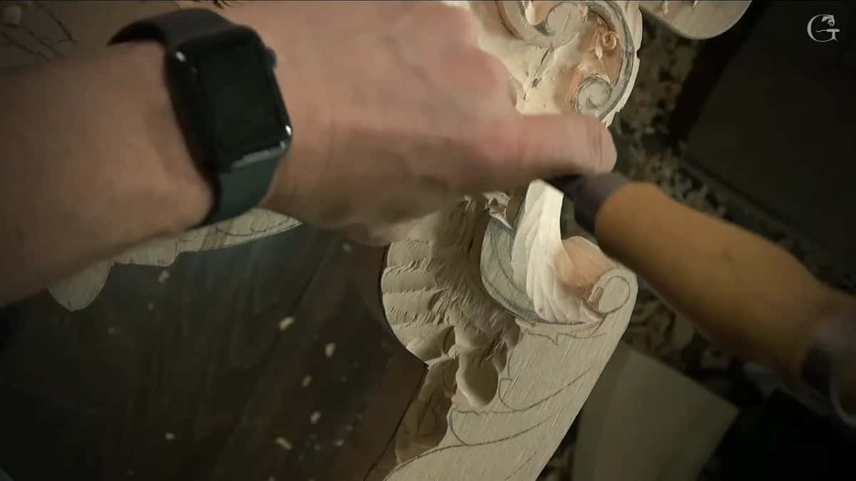 Hand presses down over a gouge near a scroll