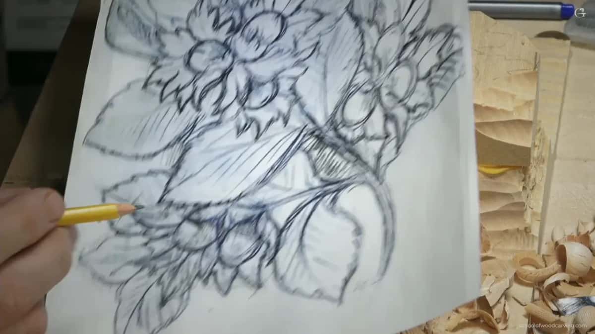 Close to the lens, the drawing of the hazelnut cluster, with a yellow pencil tip touching it