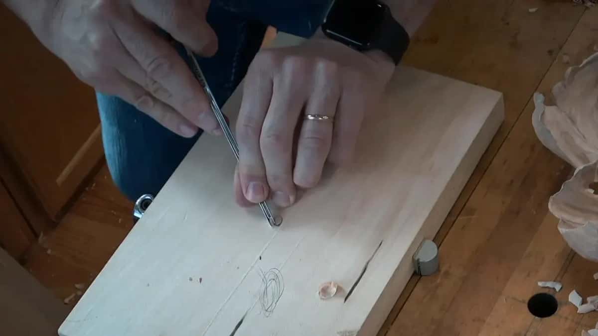 Both hands steer a narrow gouge round the little ring