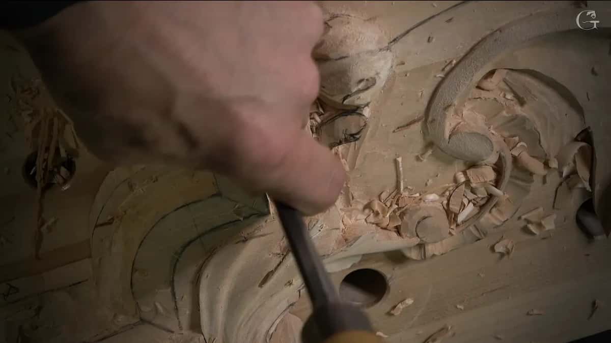 Thumb and fingers press a dark handled tool straight down beside the curved section