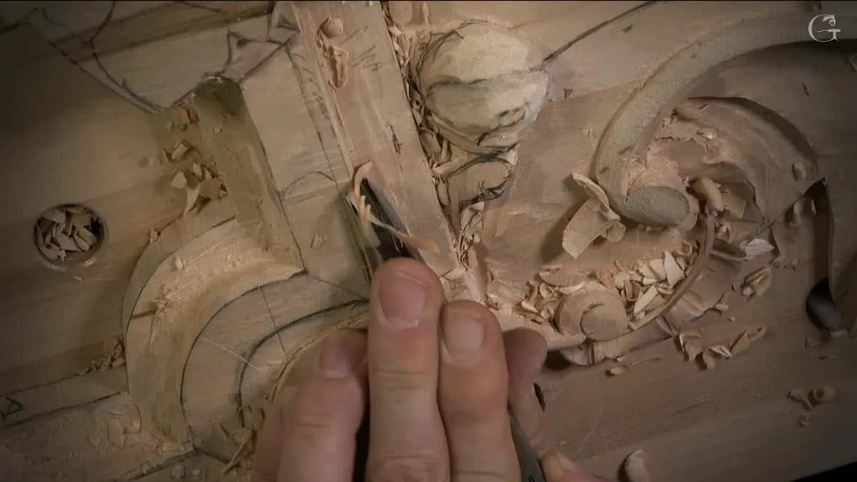 Fingers guide a narrow tool along the inside corner, chips piled to the side