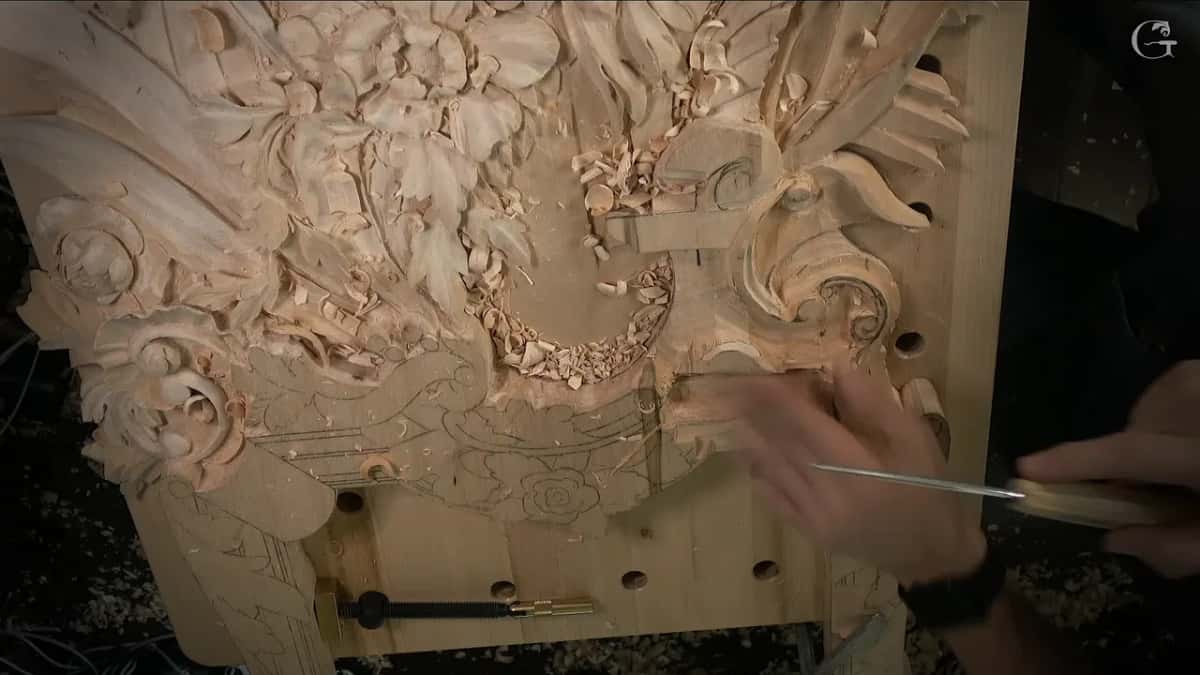 Whole panel clamped to the bench while a small gouge works the drawn lower part