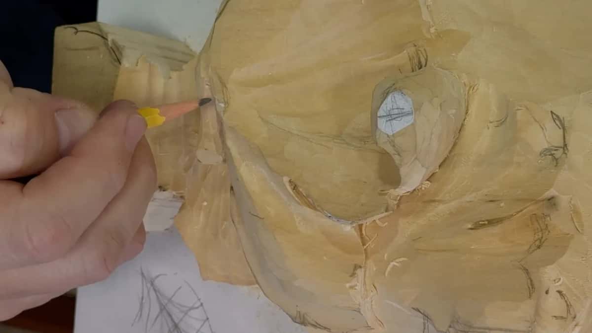 A yellow pencil marks the edge of a carved leaf, beside a small white oval scribbled over in pencil.