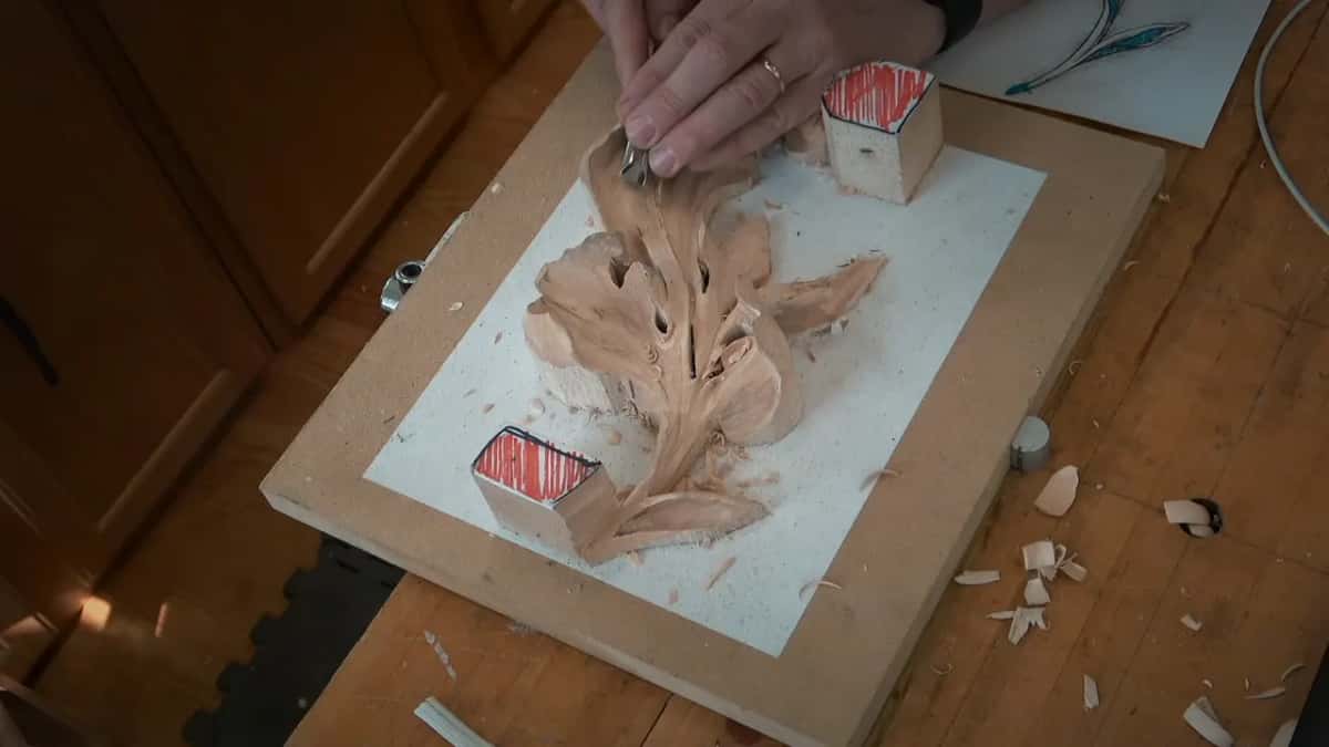 One hand sits on the top lobe, a tool under the fingers, beside the upper red block