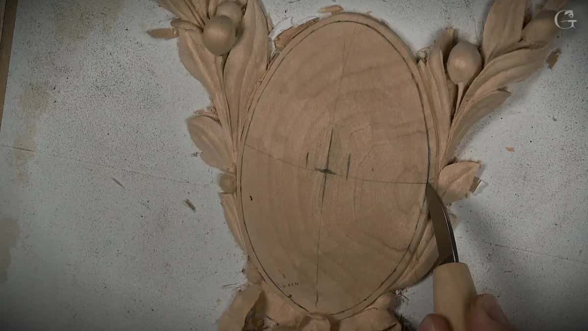 Knife following the line around the oval, its center marked with a pencil cross