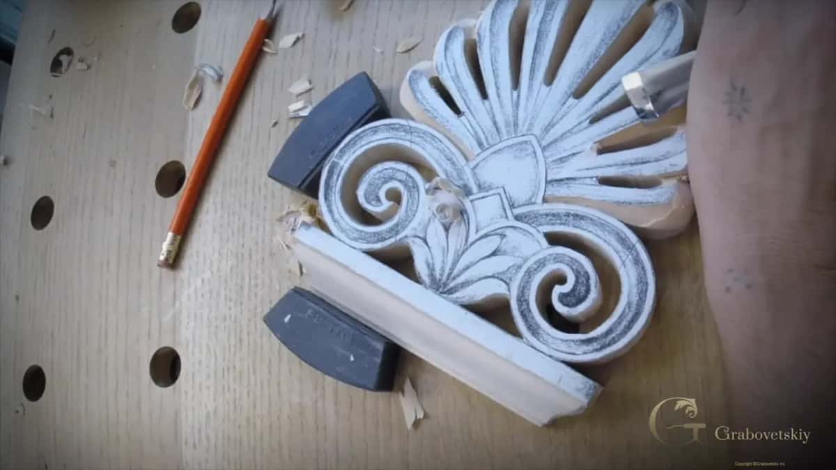 Whole fan with both spirals and the base, held between two black stops, a pencil off to the left