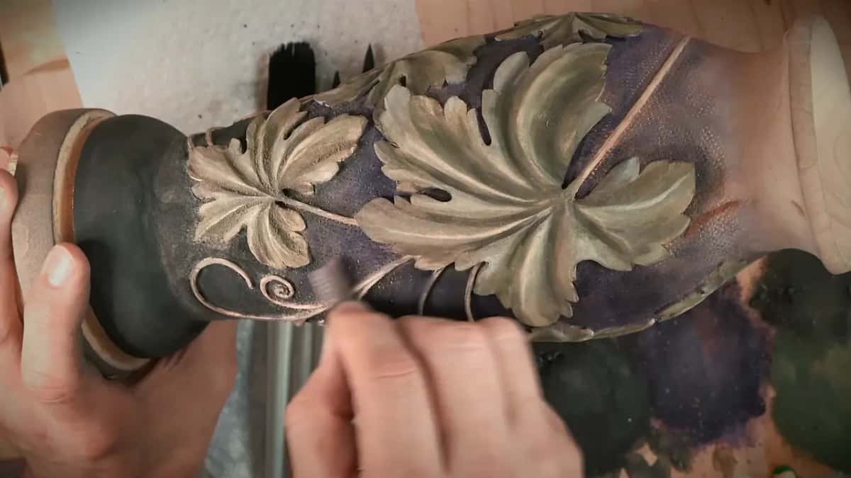 Fingers work close to the curling stems of the colored grape leaf vase.