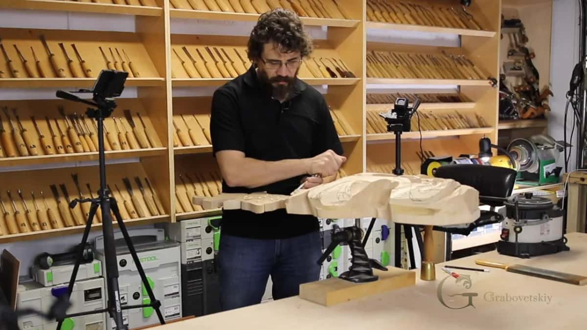 Gripping the handle up high, the blade angled down to the carving