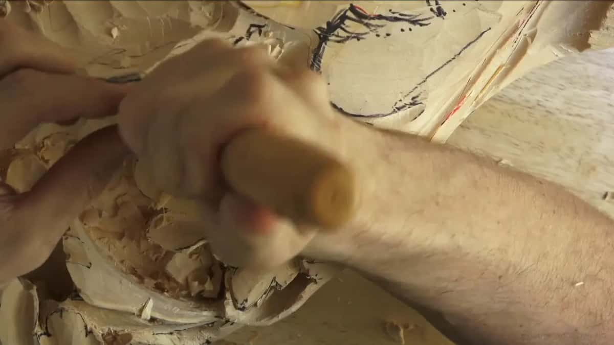 Both hands grip one handle low in the shavings